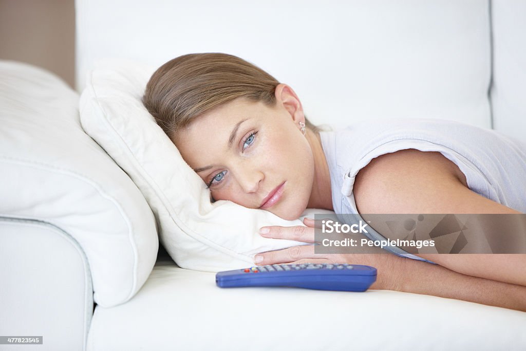 This show is so sad Attractive young woman lying on the sofa with a TV remote and looking sad Looking Stock Photo