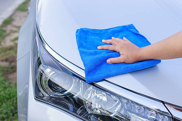 istock Woman hand with blue microfiber cloth cleaning the car 477824324