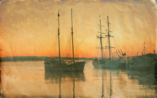 Grungy photo of old sailing ships  at sunset.  Oslo harbor, Norway. Processed with additional effects in Photoshop.Winter in the harbor. Oslo, Norway