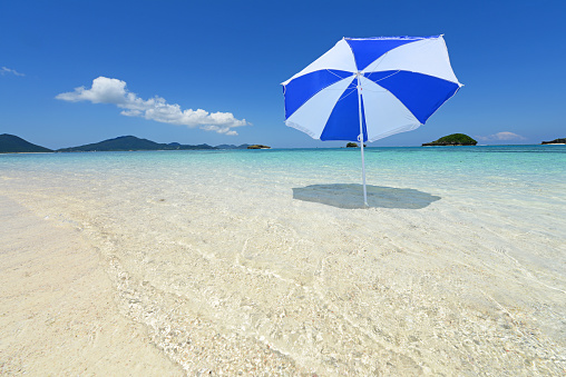 Beach with rows of sunbeds and colorful parasols.