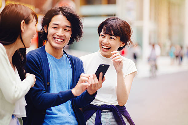 gruppe von jungen mit smartphone japanischen personen - teenager city life laughing group of people stock-fotos und bilder