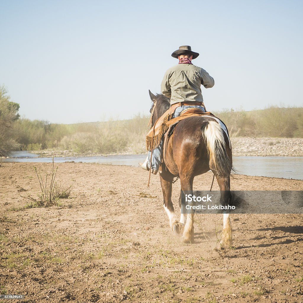 Cowboy equitazione di distanza, vicino a River - Foto stock royalty-free di Arizona