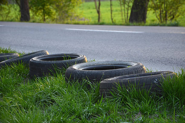 Old tyres are laid next to the empty road. Old tyres are laid next to the empty road. crud stock pictures, royalty-free photos & images