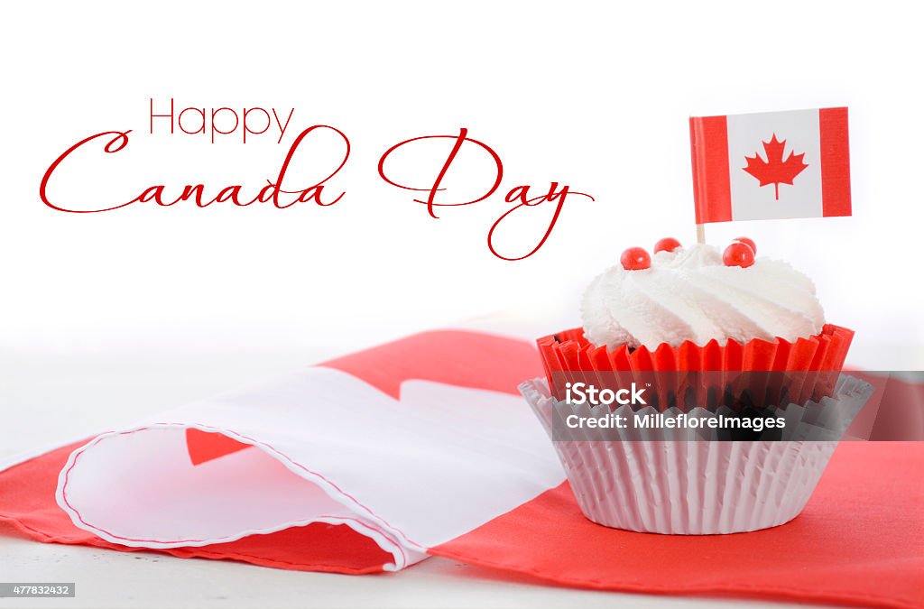 Happy Canada Day Cupcake Happy Canada Day celebration cupcake with red and white Canadian maple leaf flag on white wood table, and sample text. Canada Day Stock Photo