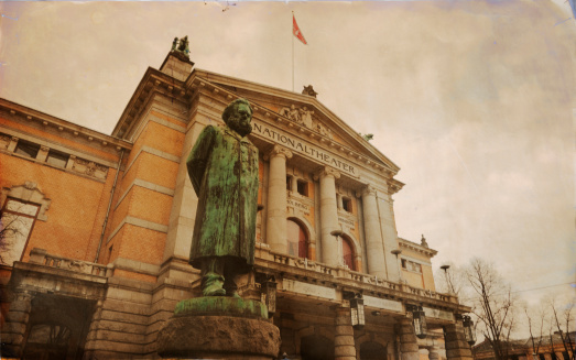 Grungy photo of the National Theatre in Oslo, Norway.  Statue of the  Norwegian writer Henrik Ibsen in front.