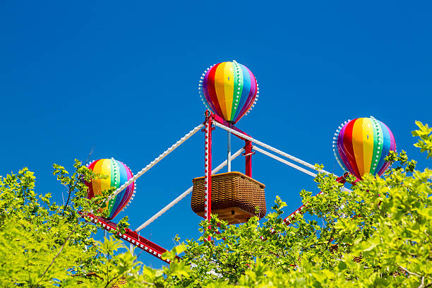 Colorful lighted balloon shapes above baskets on childrens fairground ferris wheel