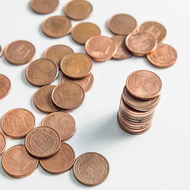 Many one cent euro coins with some on a column isolated on a white background.