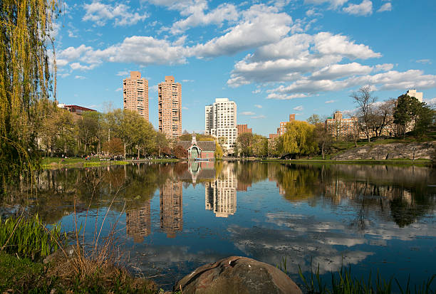 Central Park North Spring Vivid, wide angle, reflection of trees, clouds, and buildings in a Central Park lake in Harlem, New York - late day, spring harlem park stock pictures, royalty-free photos & images