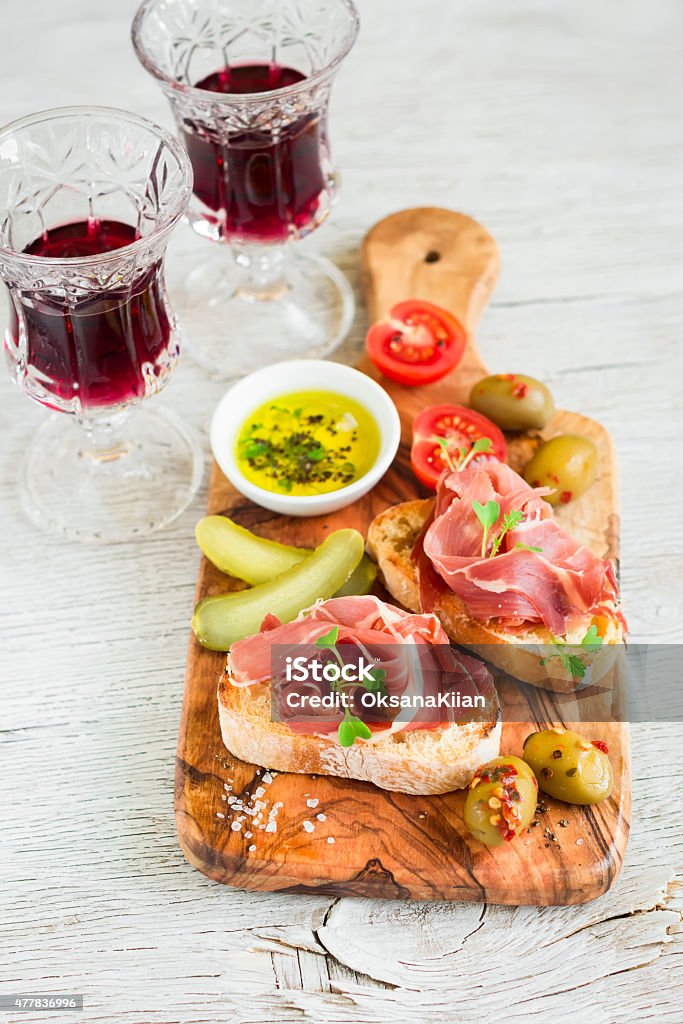 toast with ham, olives and cherry tomatoes in olive Board toast with ham, olives and cherry tomatoes in olive Board on a light wooden background Aperitif Stock Photo