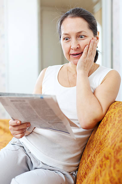 istock surprised woman with newspaper 477840735
