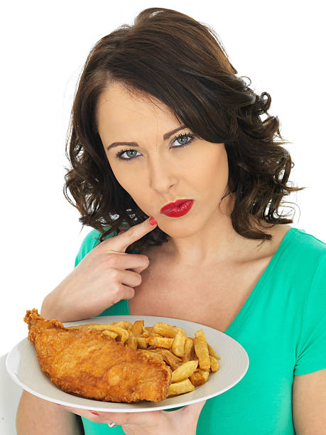 istock Young Woman Eating Traditional Fish and Chips 477840756
