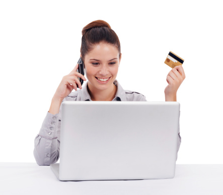 Shot of a young woman seated at a laptop and holding a credit card and cellphone