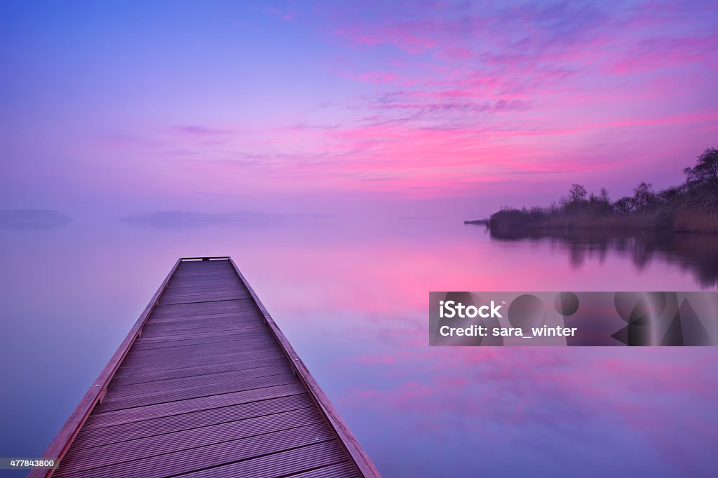 Jetty on a still lake at dawn in The Netherlands A small jetty on a still lake on a quiet morning at dawn, near Amsterdam in The Netherlands. 2015 Stock Photo