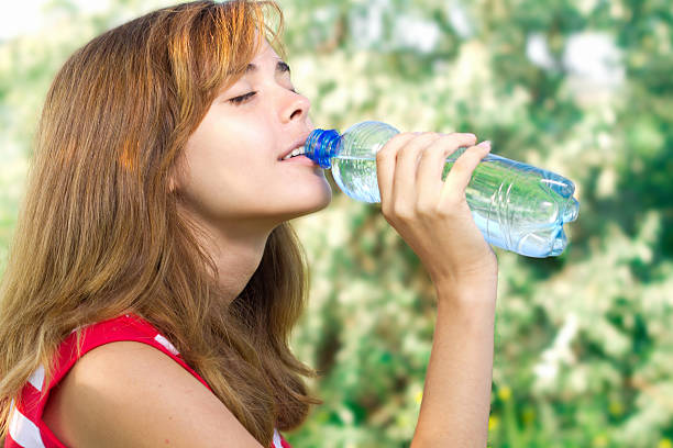 istock beautiful girl drinks water from a bottle on the nature 477843879