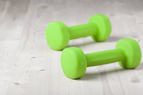 istock small green dumbbells on wooden surface 477844341