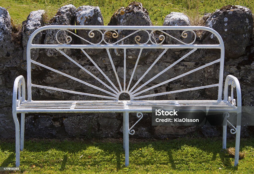 Bench White steel bench in front of a stone fence on green grass. Photograph taken at the Irish countryside. Bench Stock Photo