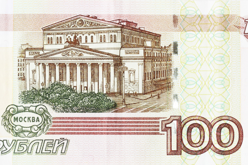 Reverse side of 100 ruble denomination Russian paper money printed in 1997 - the current currency of the Russian Federation. The image is of the facade of the Bolshoi Theater in Moscow.  The obverse side carries an image of the Quadriga statue - a four horse chariot - in front of the Bolshoi Theater.  Printed in Slavic language, the currency is minted in Moscow and St. Petersburg on high quality light pink cotton paper with multi-colored security fibers chaotically embedded throughout, plus watermarks in the right and left coupon fields. There are approximately 30 rubles to the U.S. dollar.