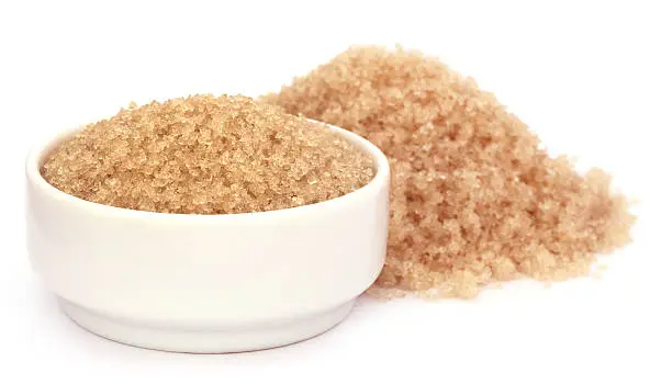 Coarse crystals of brown sugar in a white bowl