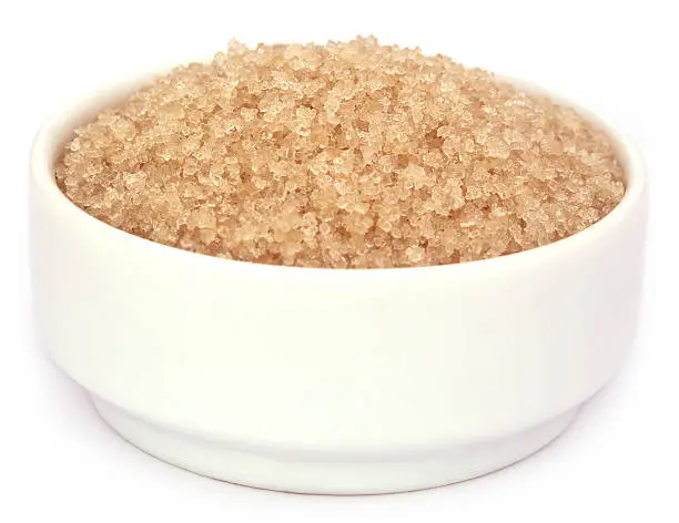 Coarse crystals of brown sugar in a white bowl