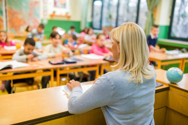 istock Rear view of elementary teacher teaching children in the classroom. 477850360