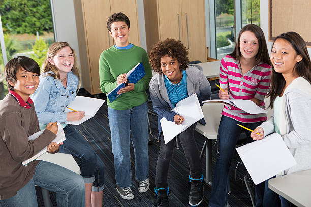 Students in classroom Multi-ethnic group of students in classroom, working together on a project. junior high stock pictures, royalty-free photos & images