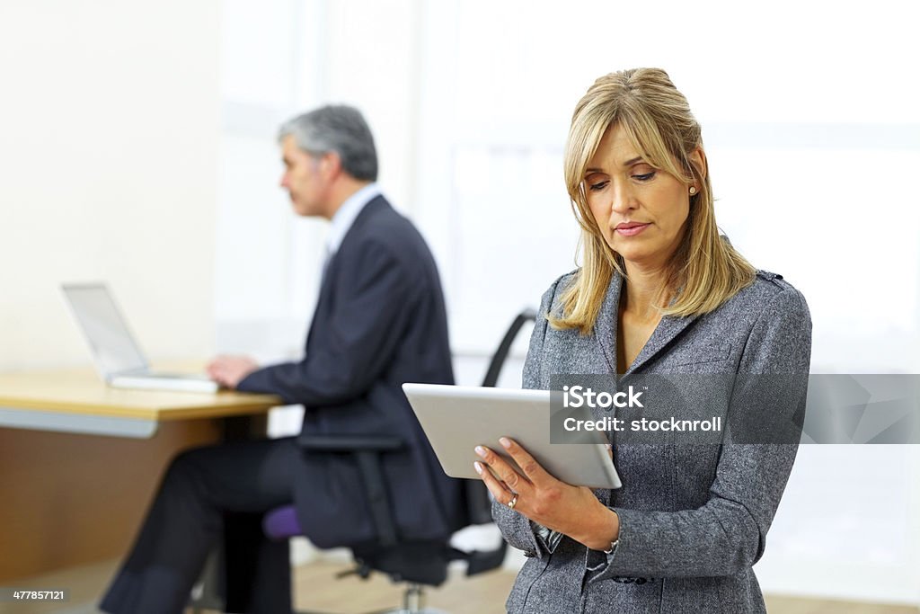 Maduro mujer ejecutiva utilizando tableta digital en oficina - Foto de stock de 40-44 años libre de derechos