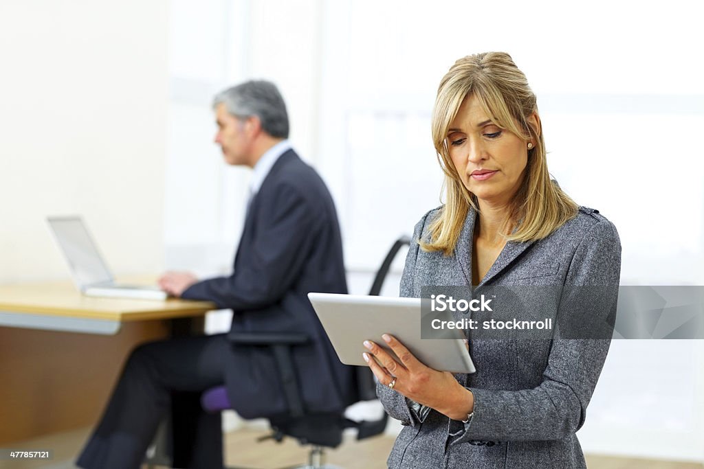 Executivo feminino maduro usando tablet digital no escritório - Foto de stock de 40-44 anos royalty-free
