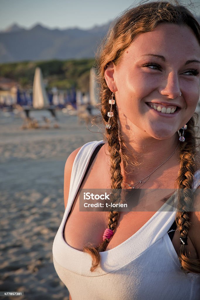 Smiling at the beach Young woman smiling and looking at person out of image. Sunset time in Italy Adult Stock Photo