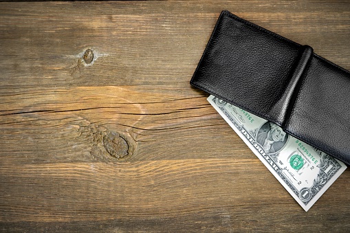 Open Male Black Leather Wallet With USA One Dollar Bill On Old Rough Brown Wood Background With Copy Space