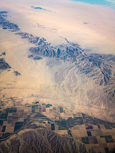 mobilestock aerial landscape the interface of mountains and farmland across the desert floor are laid bare near yuma, arizona.  horizontal wide angle and high angle airborne mobilestock composition. yuma photos stock pictures, royalty-free photos & images