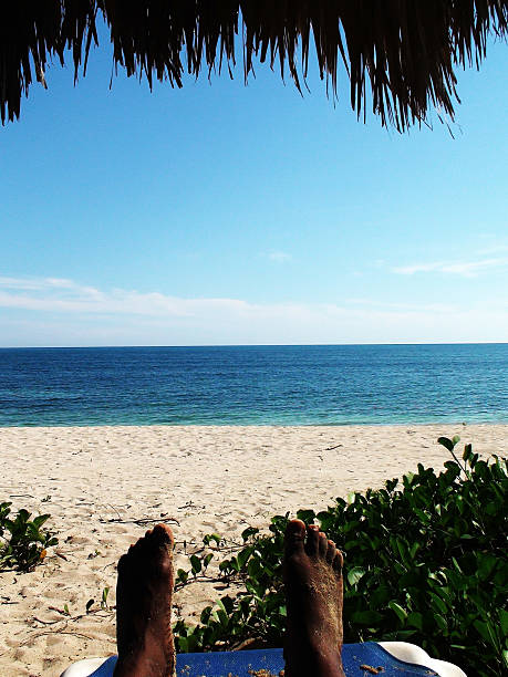Man With Sandy Feet Resting On The Warm Caribbean Beach
