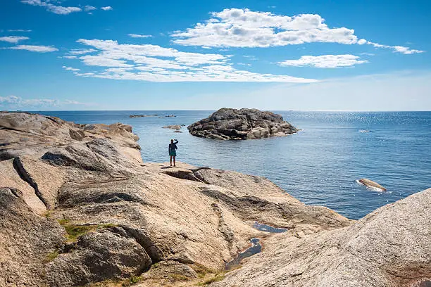 Slope of naked rock with a woman looking at the view at Verdens Ende, Tjøme Vestfold, Norway