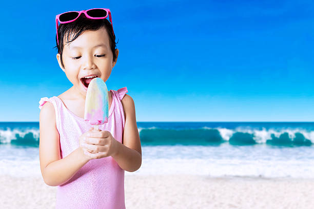 istock Excited girl eats ice cream at shore 477859212