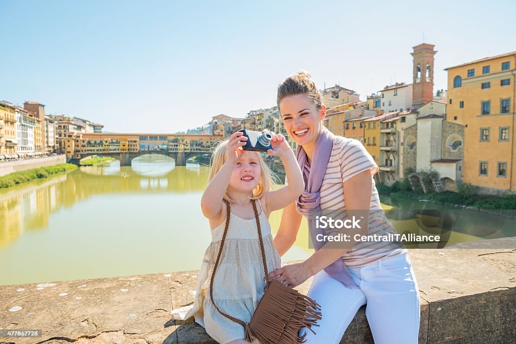 Mother and baby girl taking photo in florence Mother and baby girl taking photo while standing on bridge overlooking ponte vecchio in florence, italy Florence - Italy Stock Photo