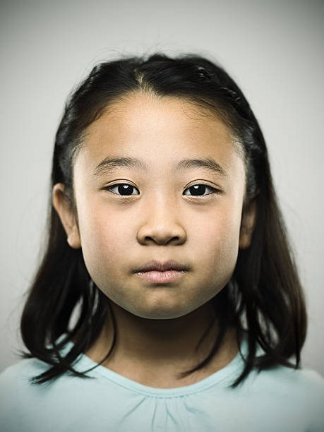 Portrait of a young japanese girl looking at camera. Studio portrait of a japanese young girl with relaxed expression looking at camera. The girl has 10 years and has long hair and casual clothes. Vertical color image from a medium format digital camera. Sharp focus on eyes. child japanese culture japan asian ethnicity stock pictures, royalty-free photos & images