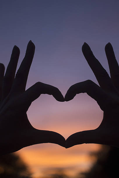 istock Heart shape hands at dusk silhouette sunset sky 477868402