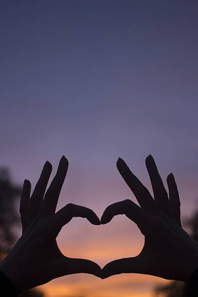 istock Heart shape hands at dusk silhouette sunset sky 477871096