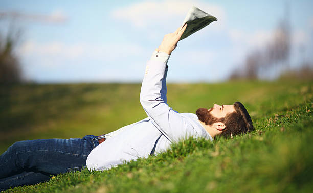 homem lendo jornais enquanto relaxa no parque. - reading newspaper 30s adult - fotografias e filmes do acervo