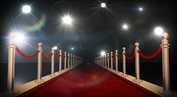 Red carpet with gold barriers, velvet ropes and flashlights in the background. 3D rendering in 16bit.