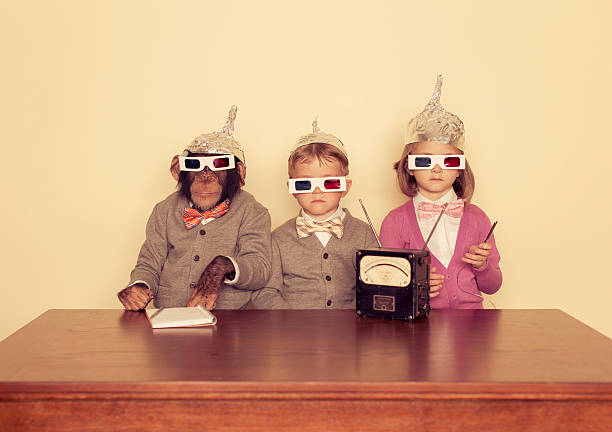 Young Children and Chimpanzee wear Tinfoil Hats A group of friends and their chimpanzee are trying to communicate with higher intelligence. serious monkey stock pictures, royalty-free photos & images