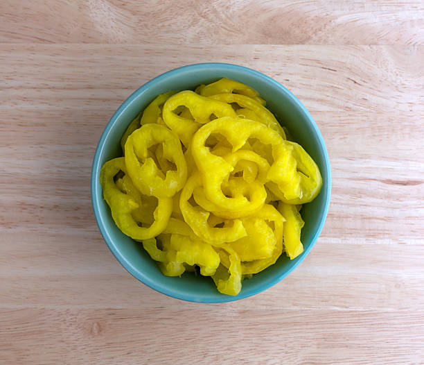 Banana peppers in a bowl on a wood table