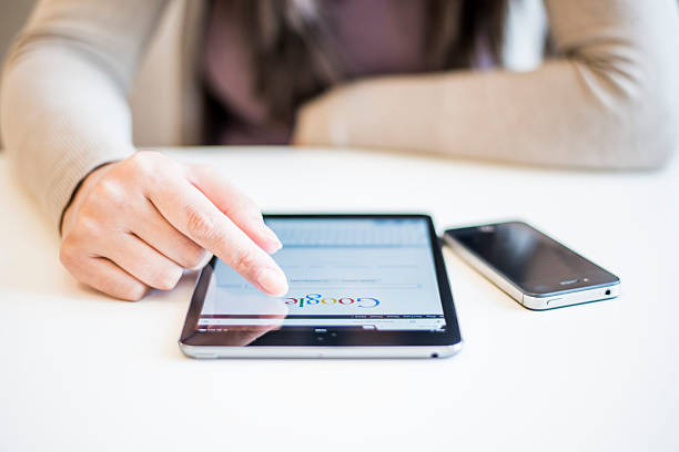 Woman holding Ipad Mini Novi Sad, Serbia - October 6, 2014: Woman's hands Googling on electronic device.Woman hands holding and touching on Apple iPad mini with Google search web page on a screen. brand name photos stock pictures, royalty-free photos & images