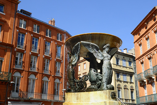 view of French brick buildings and fountain in Toulouse, place de la Trinite.