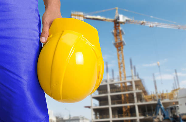 Yellow helmet at builder hands on building background stock photo