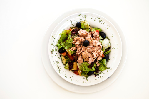 Tuna salad with letuce, tomato and olives on a white background