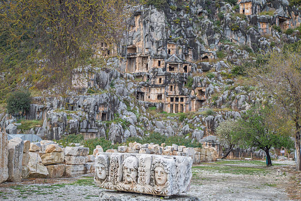 View of Byzantine carved stone faces in Myra, Antalya Province, Turkey. Ancient tombs and hillside in background