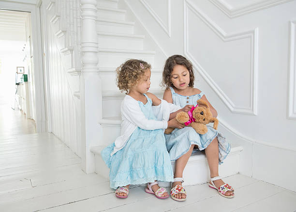 Two vintage dolls sitting side by side on a pink background