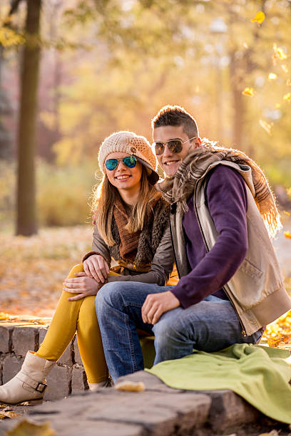 istock Smiling couple sitting in autumn park and looking at camera. 477888638