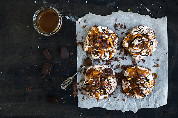 istock Salted caramel and chocolate meringues over dark grunge surface, top 477893540