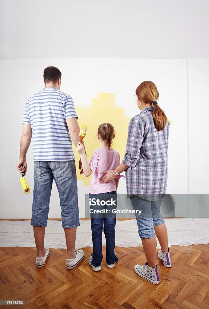 Family looking at paint sample on the wall. Rear view of family looking at the paint sample on the wall. 30-39 Years Stock Photo